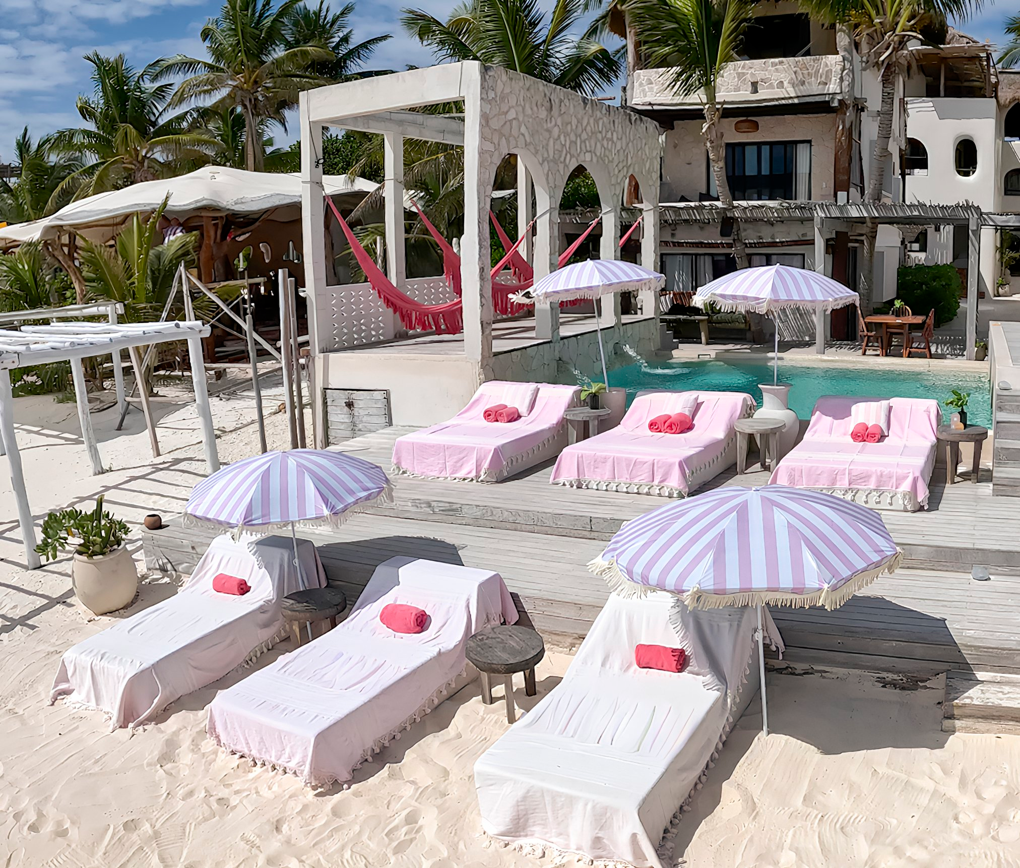 Aerial view of pink striped umbrellas and loungers at Chi Ka Tulum